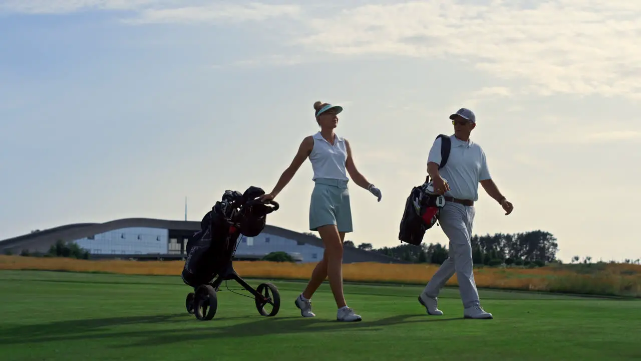 Dos Golfistas Caminan Por La Calle Al Atardecer Pareja Rica Lleva Clubes De Equipamiento Deportivo