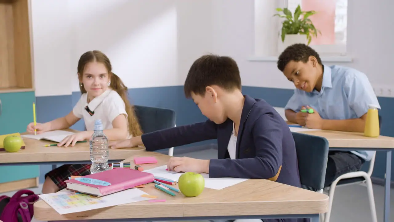 Estudiante Masculino Sentado En El Escritorio En El Aula De Inglés Escribiendo En Su Cuaderno 2