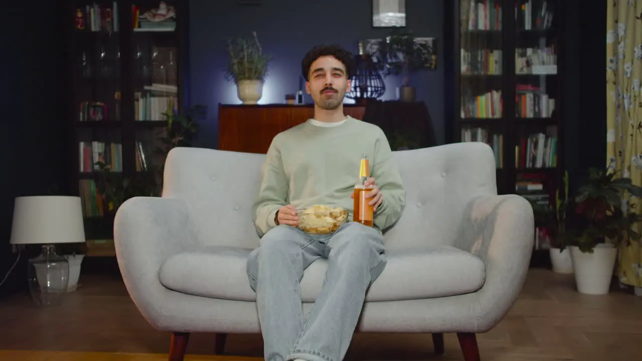 Joven Viendo Una Película Interesante En La Televisión Mientras Come Papas Fritas Y Bebe Refrescos Sentado En El Sofá En Casa