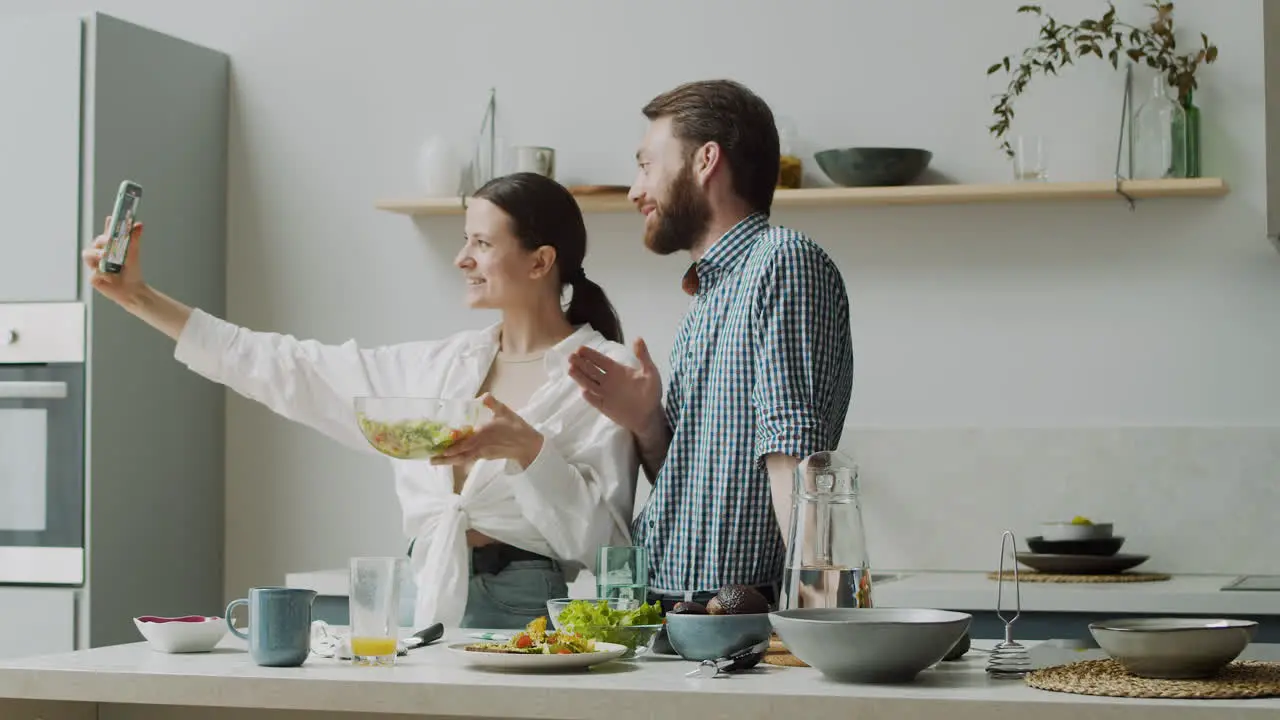 Fröhliches Paar Das In Einer Modernen Küche Ein Selfie-Foto Mit Salat Macht