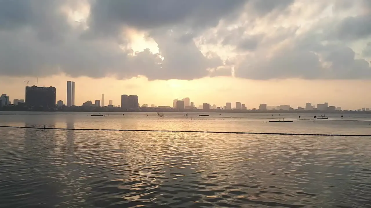 an astonishing view of the sunset and the drifting clouds above the water with the city on the background