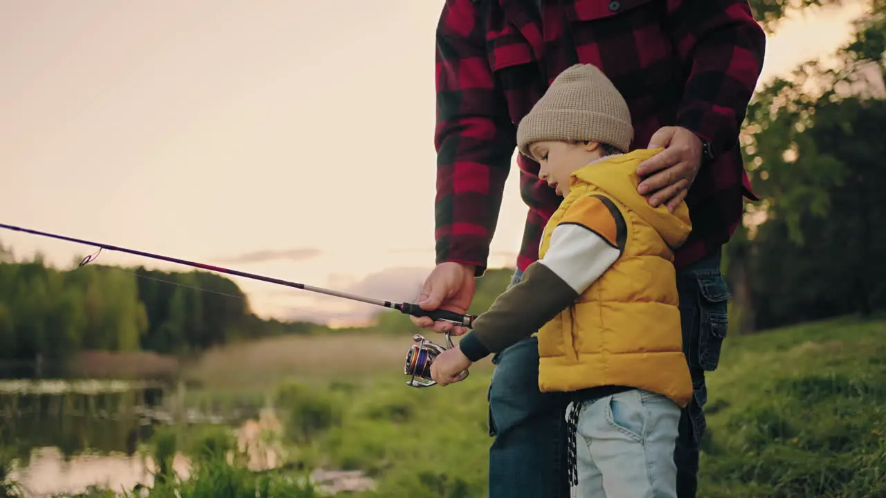 grandfather and little boy are resting on shore of lake and fishing rest in nature in spring or summer