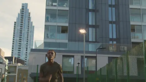 Male Football Player Heading Ball On Artificial Soccer Pitch In Urban City Area 