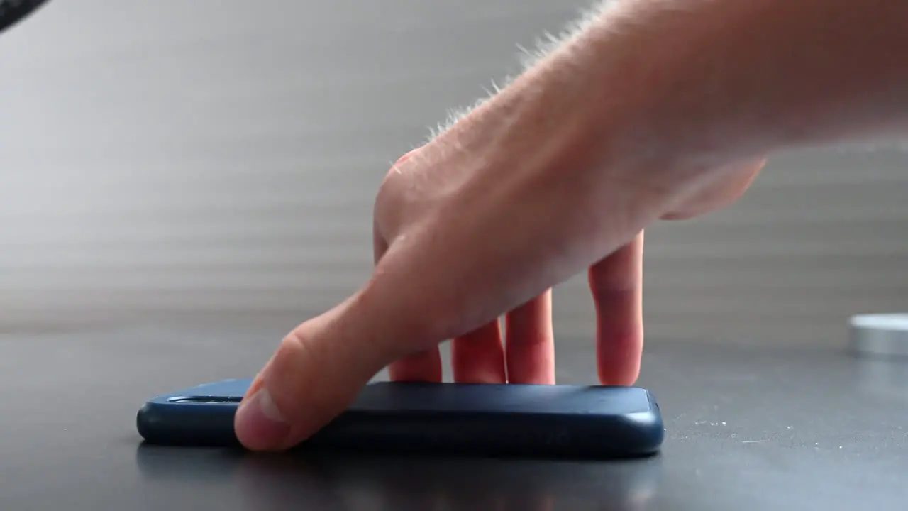 A phone user puts his mobile upside down on the table to stay focused and not get distracted