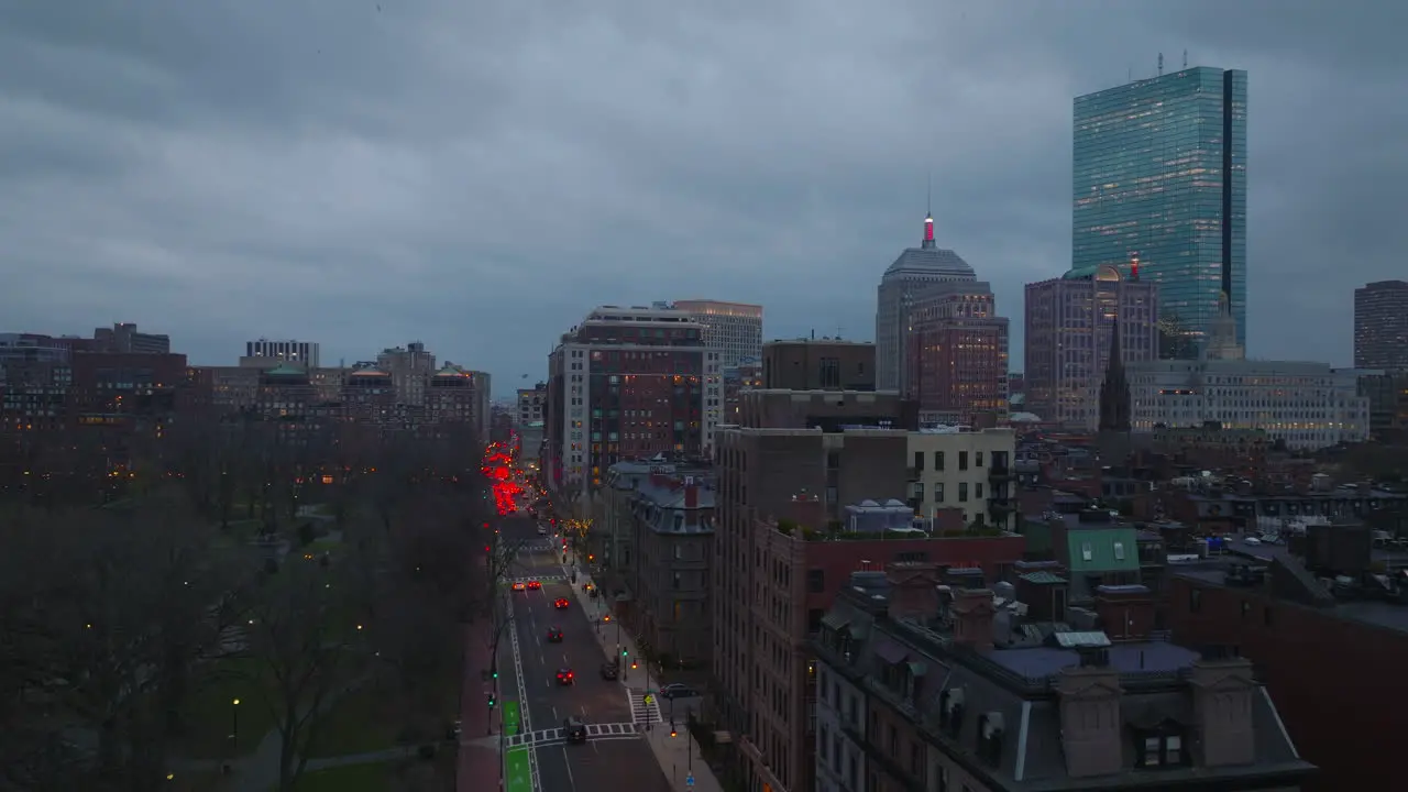 Evening flight above park and buildings in urban borough Traffic on streets Modern high rise building against sky at dusk Boston USA