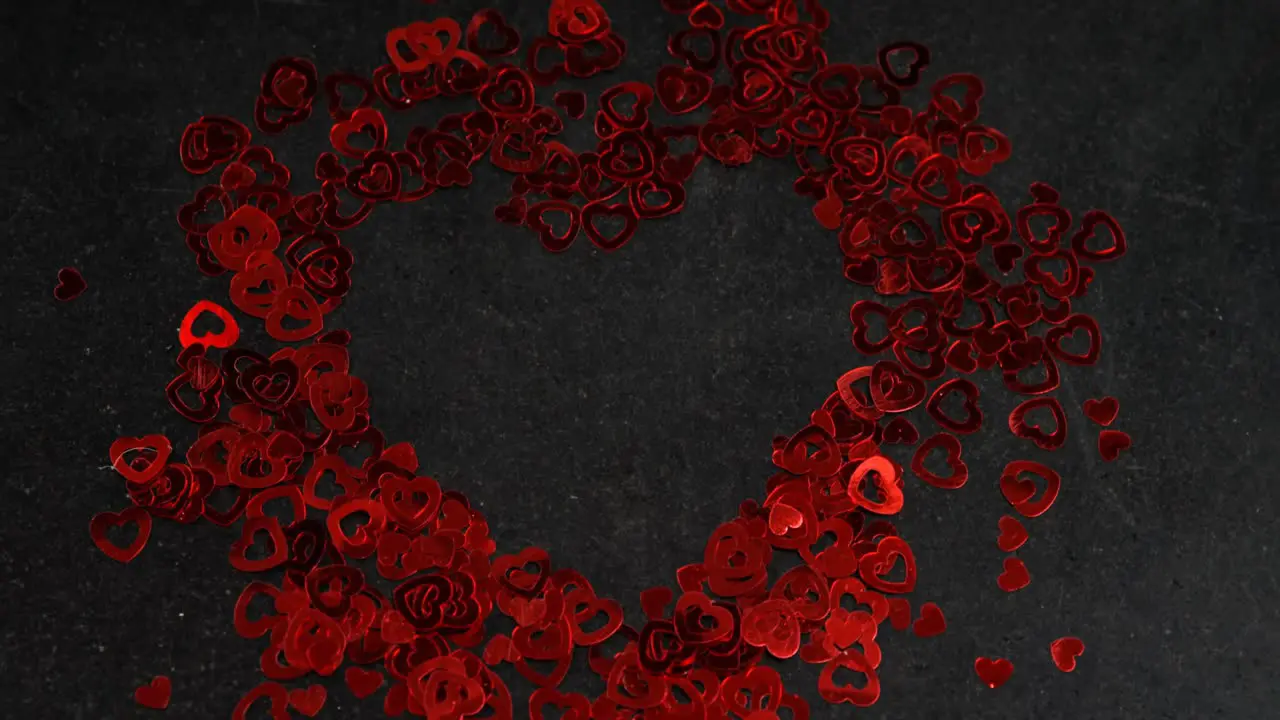 Heart shape confetti on black surface in heart formation 4k