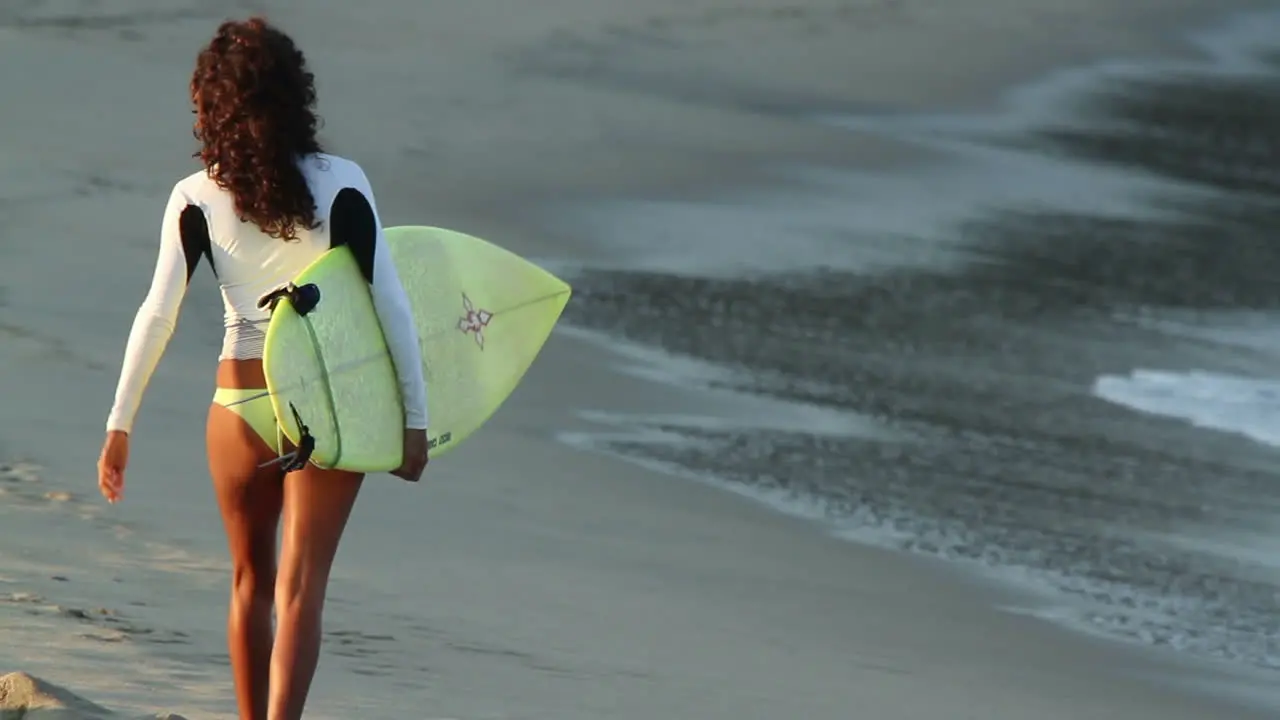 Surfer Woman walking along beach