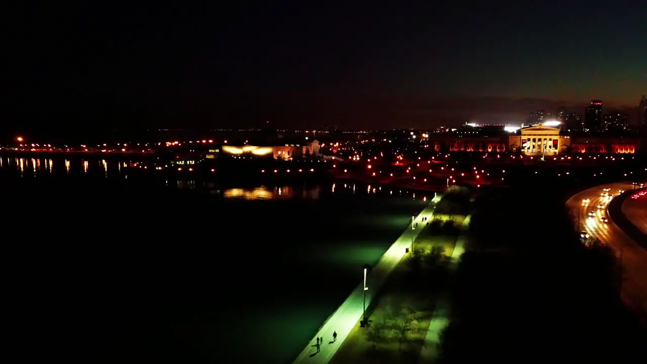 Low fly along urban waterfront at night with light reflections in the water