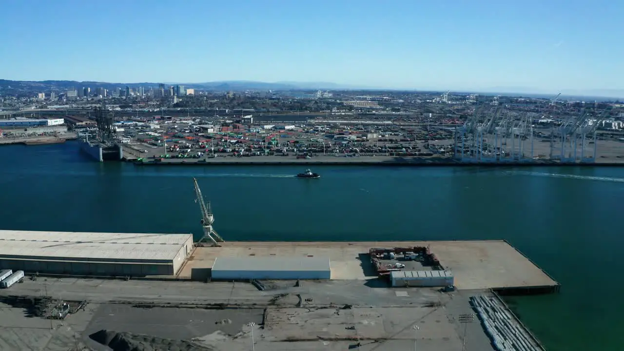 Tracking a small boat in front of the giant shipping cranes on a sunny day near the city of the bay