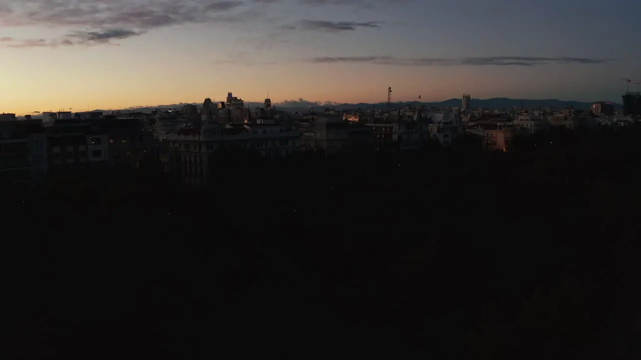 Landing footage of city after sunset Silhouettes of buildings and trees against colourful twilight sky