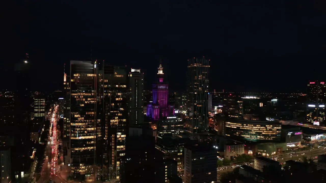 Aerial panoramic footage of city centre with high rise buildings at night Color illuminated historic Palace of Culture and Science Warsaw Poland