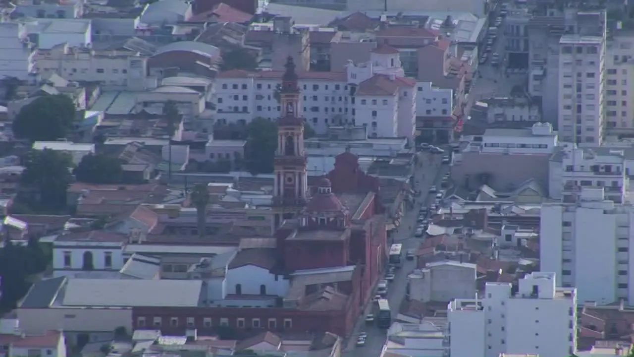 Cars and people move around the streets of a city among tall buildings