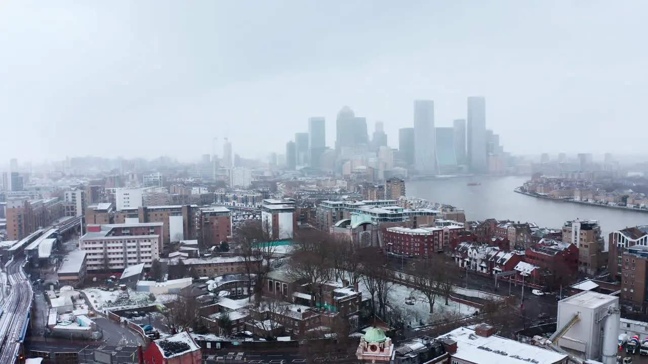 Drone shot in snow towards Canary Wharf from Limehouse London