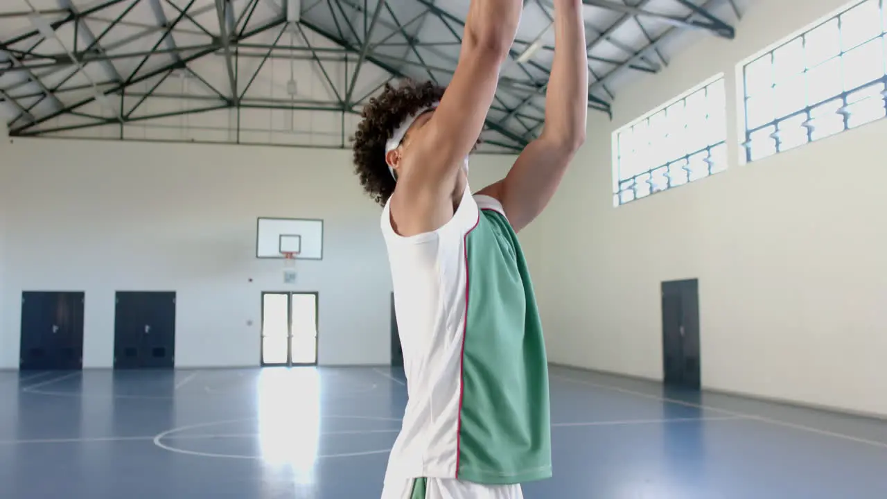 Young biracial man practices basketball in an indoor court