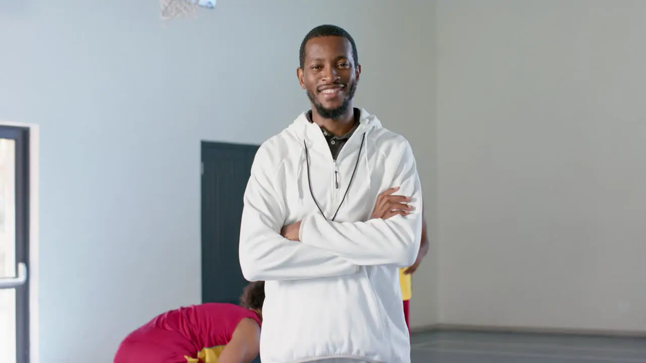 African American coach stands confidently in a gym