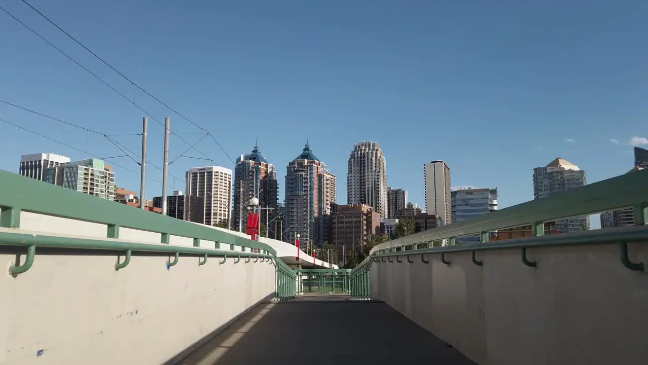 City skyscrapers approached from a pedestrian bridge on a sunny day low angle Calgary Alberta Canada