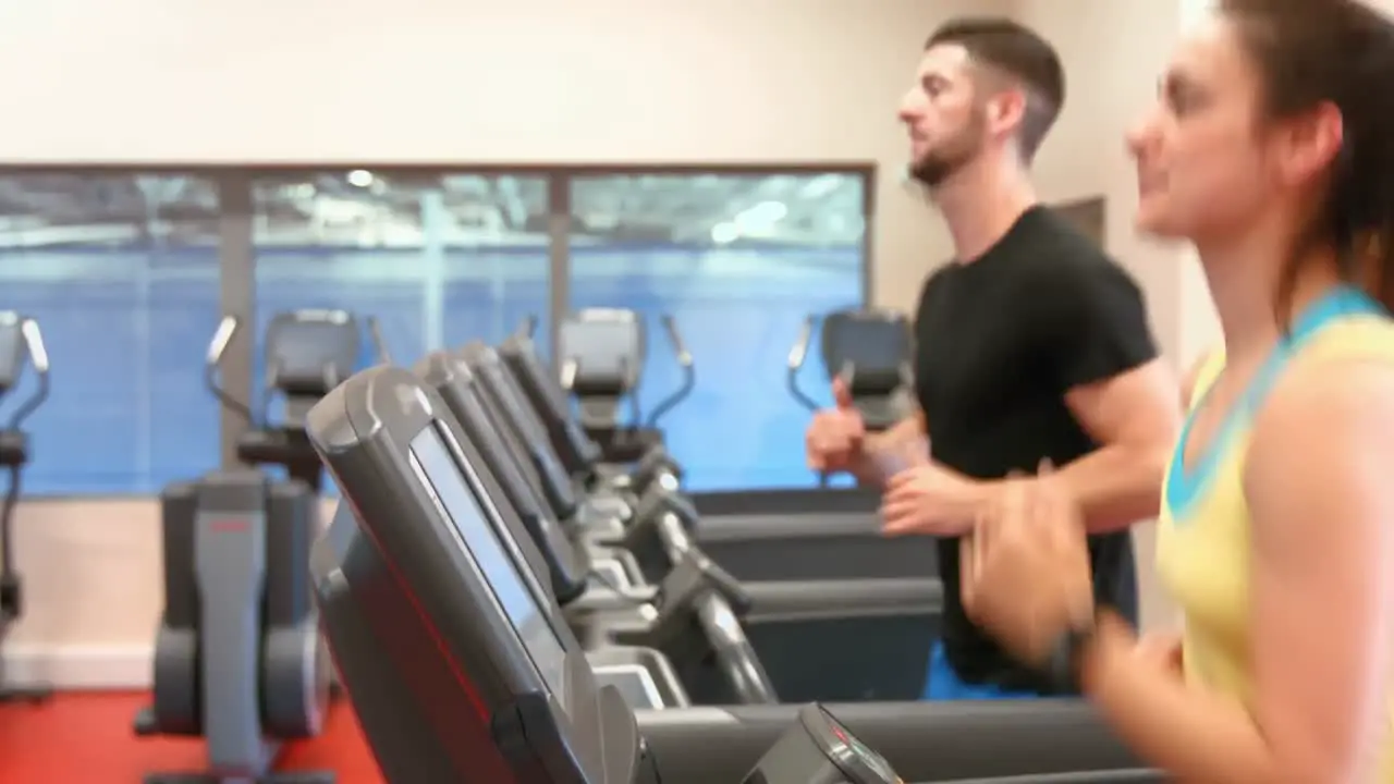 Couple using the treadmills in gym