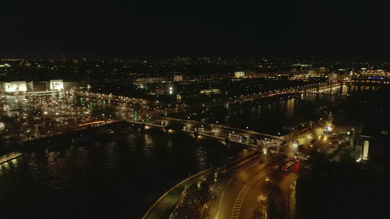 Aerial footage of evening city Vehicles driving on Pont de la Concorde and Seine river waterfronts Paved square Place de la Concorde with Luxor Obelisk in middle Paris France