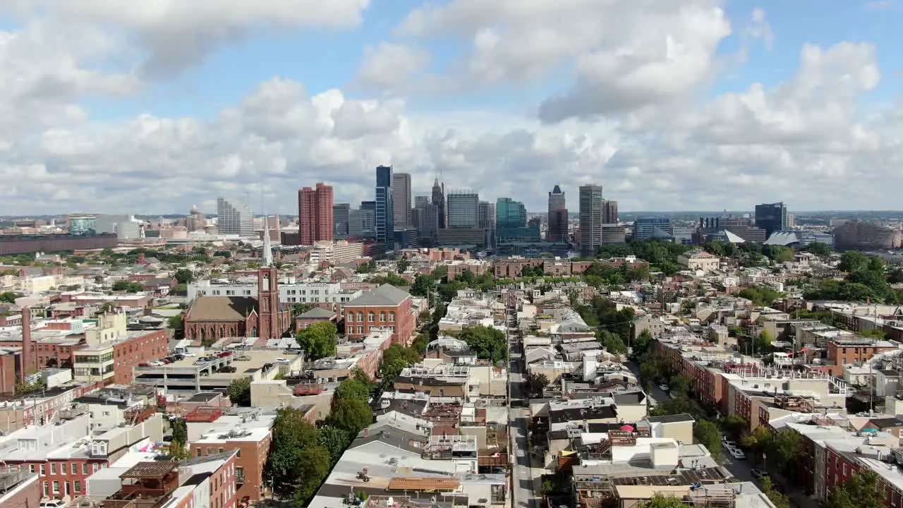 Aerial truck shot Baltimore Maryland USA skyline cityscape on summer day downtown financial business district neighborhood homes and community housing in foreground