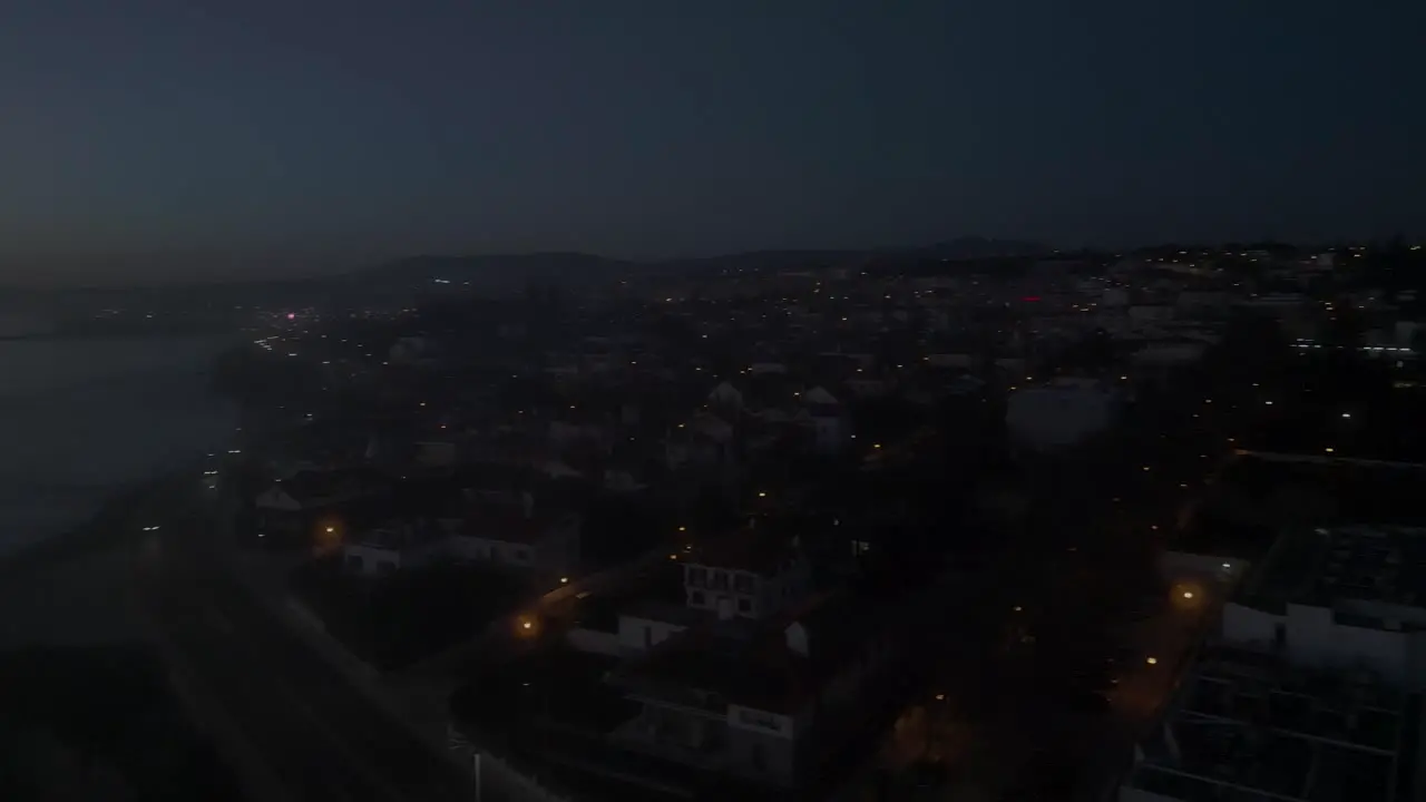 Aerial tracking drone shot of marginal at the coast of Estoril at night time in Lisbon Portugal