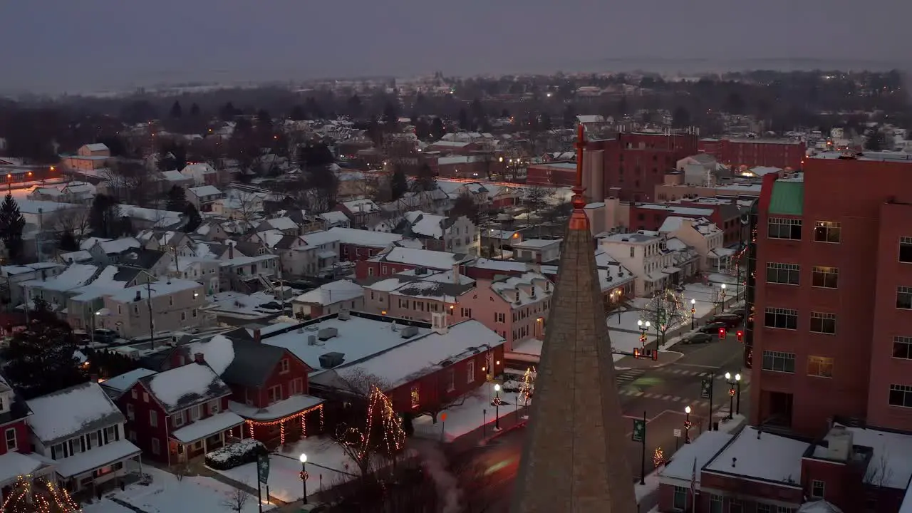 Aerial of ambulance with lights driving through snow covered town in USA at night during holiday season