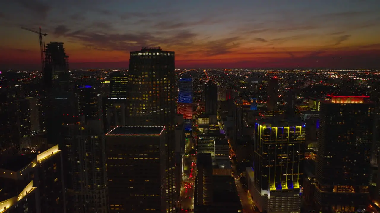 Forwards fly above evening city Tall downtown skyscrapers and endless illuminated streets in urban boroughs View against romantic colourful twilight sky Miami USA