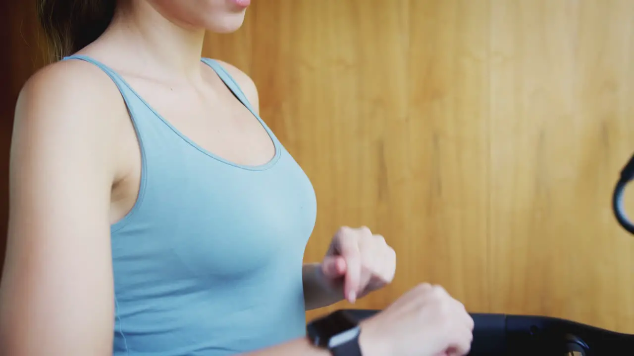 Woman Exercising On Treadmill At Home Wearing Wireless Earphones Checking Smart Watch