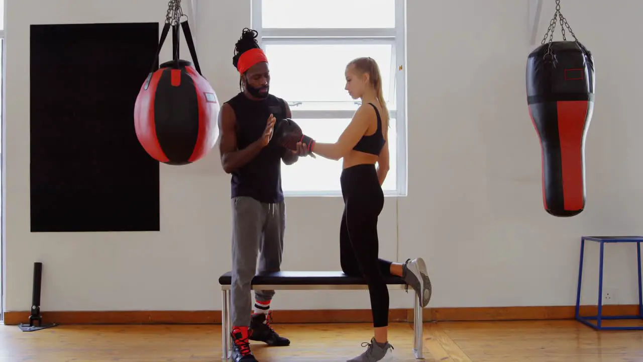 Trainer training female boxer in fitness studio 4k