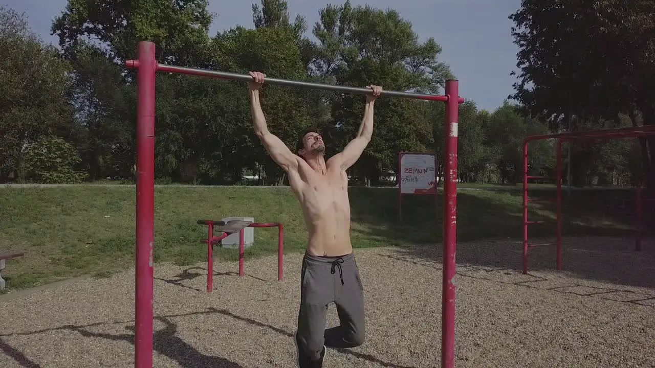 Male person doing pull ups on the bar in the park