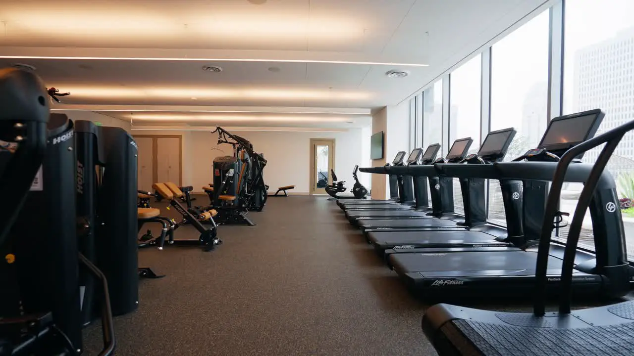 Pushing into a well-equipped fitness center highlighting cable machines and a row of treadmills for various workout options