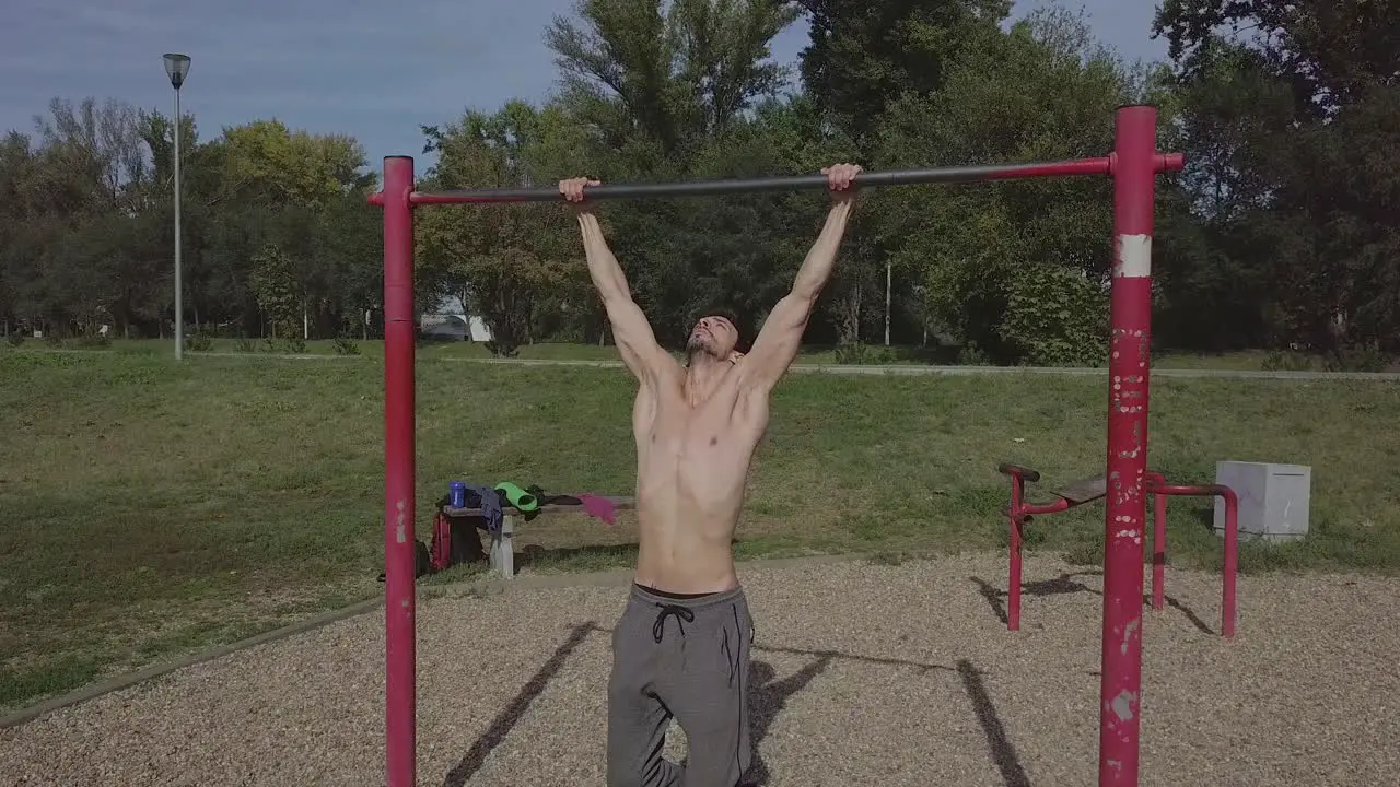 Beautiful muscular young Caucasian man doing pull ups in nature alone during individual practice