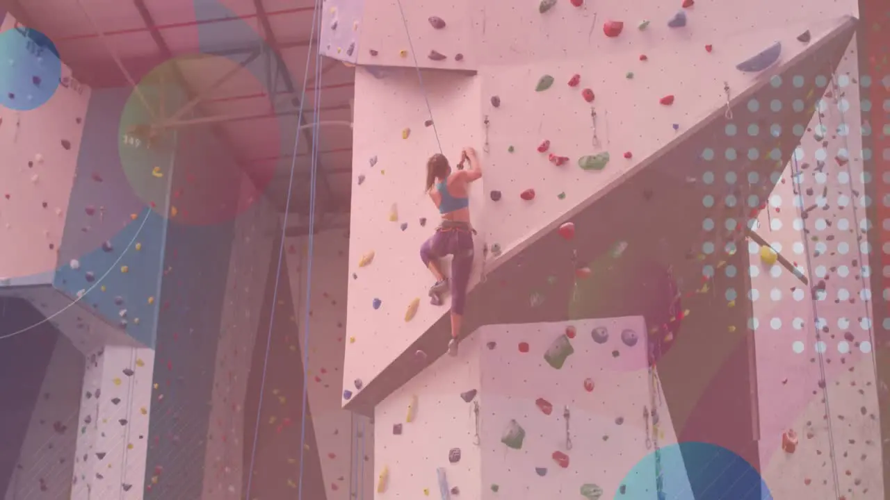 Abstract colorful shapes against caucasian fit woman wall climbing at the gym