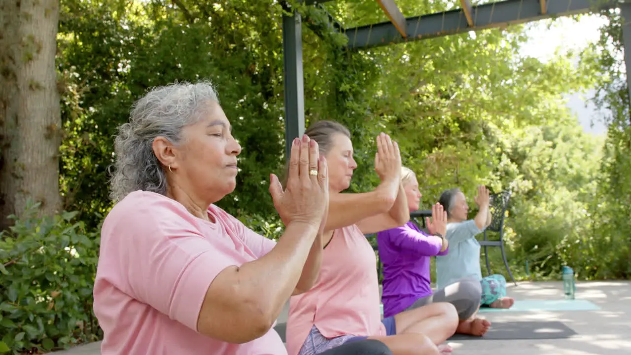 Senior biracial woman and Caucasian women practicing yoga outdoors