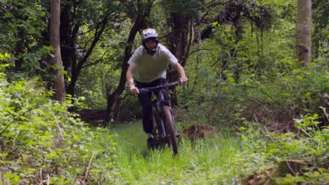 Slow Motion Shot Of Man On Mountain Bike Making Mid Air Jump On Dirt Trail Through Woodland 11