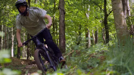 Slow Motion Shot Of Man On Mountain Bike Making Mid Air Jumps On Dirt Trail Through Woodland 2