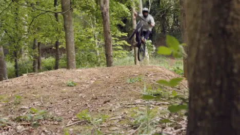 Slow Motion Shot Of Man On Mountain Bike Making Mid Air Jump On Dirt Trail Through Woodland 2