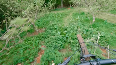 POV Shot Of Man On Mountain Bike Doing Mid-Air Jump On Trail Through Woodland