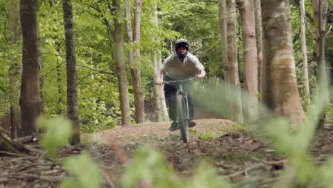 Slow Motion Shot Of Man On Mountain Bike Making Mid Air Jump On Dirt Trail Through Woodland 4