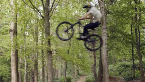 Slow Motion Shot Of Man On Mountain Bike Making Mid Air Jump On Dirt Trail Through Woodland 3