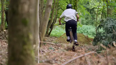 Slow Motion Shot Of Man On Mountain Bike Making Mid Air Jump On Dirt Trail Through Woodland 5