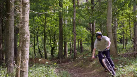 Slow Motion Shot Of Man On Mountain Bike Making Mid Air Jumps On Dirt Trail Through Woodland 3