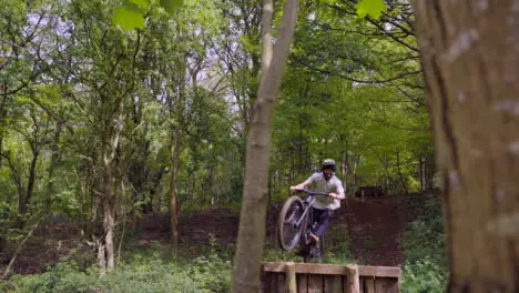 Slow Motion Shot Of Man On Mountain Bike Making Mid Air Jumps On Dirt Trail Through Woodland 7