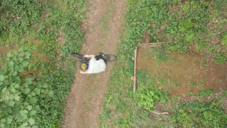 Drone Aerial Shot Of Man On Mountain Bike Doing Mid-Air Jump On Trail Through Woodland 