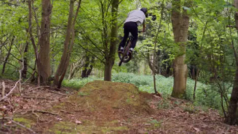 Slow Motion Shot Of Man On Mountain Bike Making Mid Air Jump On Dirt Trail Through Woodland 9