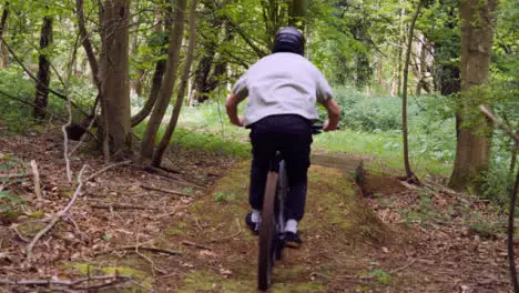 Slow Motion Shot Of Man On Mountain Bike Making Mid Air Jump On Dirt Trail Through Woodland 8