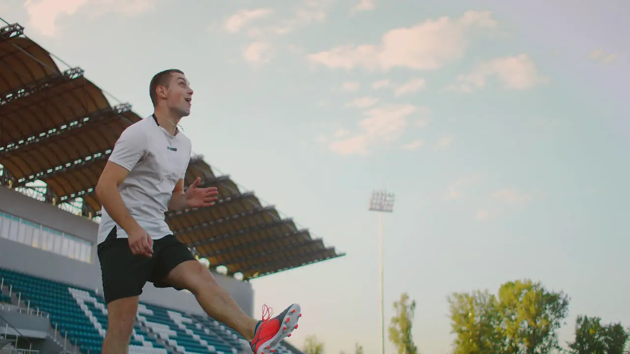 Tilt up with slow motion of male from professional soccer league juggling ball on leg in outdoor playing field on sunny summer day