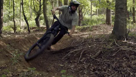 Slow Motion Shot Of Man On Mountain Bike Cycling Along Dirt Trail Through Woodland 