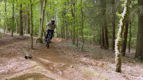 Man On Mountain Bike Cycling Along Trail Through Countryside And Woodland 2