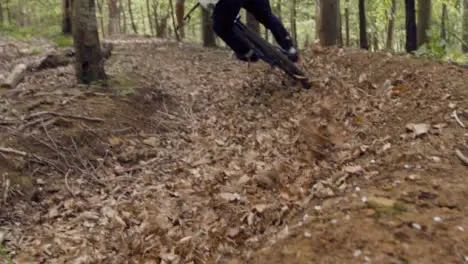 Low Angle Shot Of Man On Mountain Bike Cycling Along Dirt Trail Through Leaves In Woodland 2