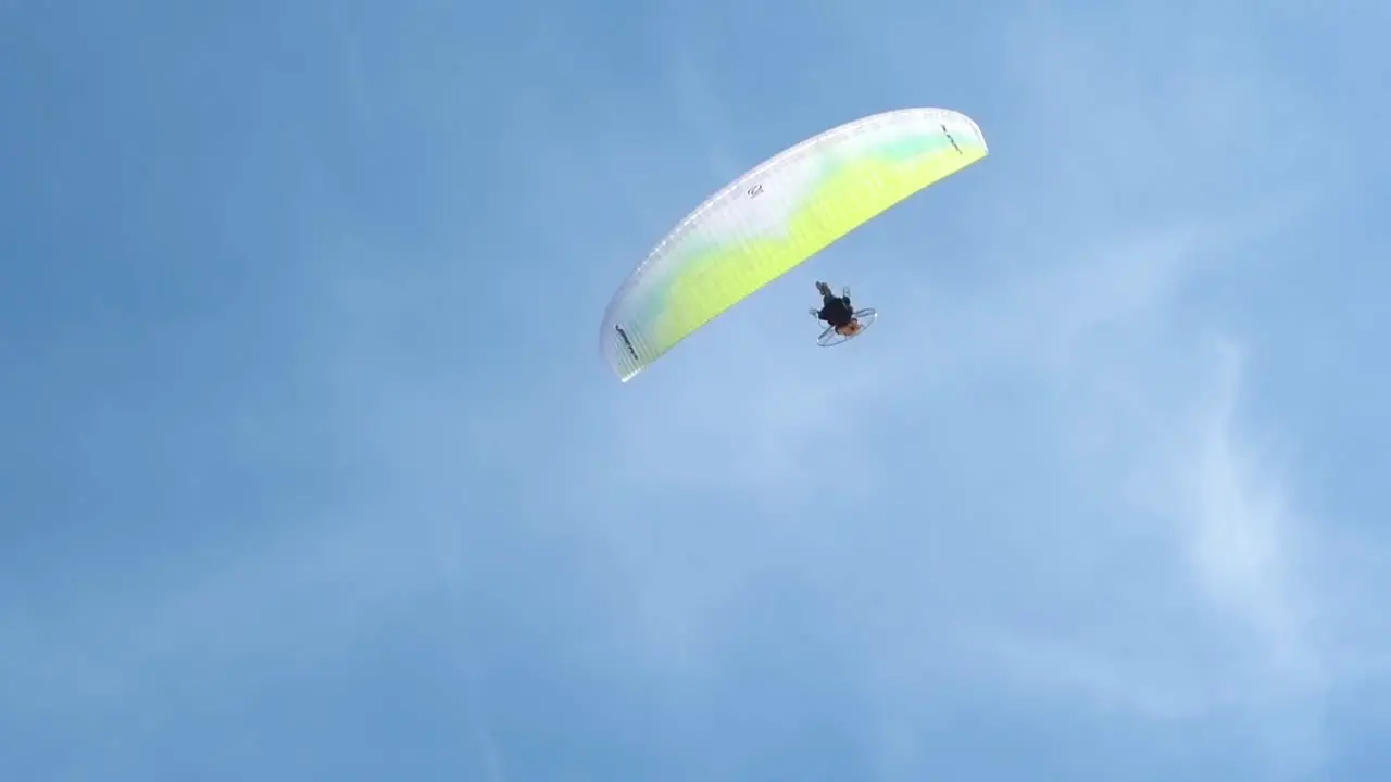 Paraglider passing overhead in the blue sky